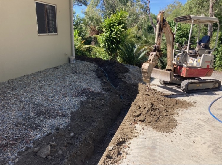 A drainage trench cut and bedded alongside a house