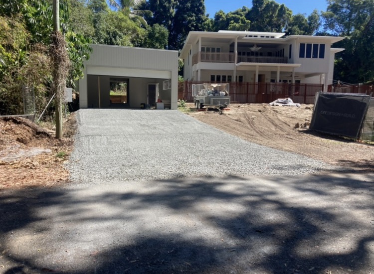Newly formed gravel driveway running up to a shed beside a house under construction