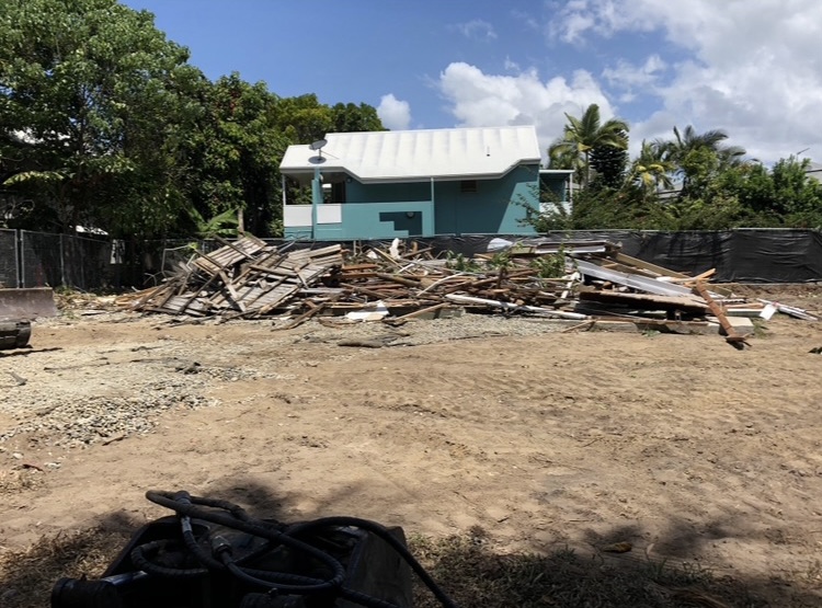 Demolition site cleared back to a pad, timber debris stacked ready to cart away